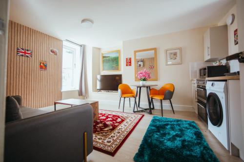 a living room with a couch and a table with orange chairs at KENDAL HOLIDAY FLATS in Kendal
