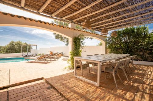 een patio met een tafel en stoelen en een zwembad bij B&B Casa do Cerro in Moncarapacho