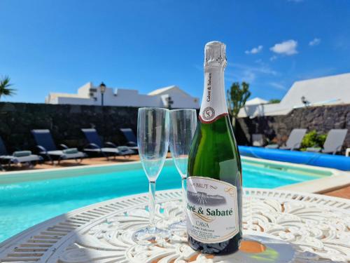 a bottle of champagne and two glasses on a table by a pool at Villa Lagarto heated pool aircon central Playa Blanca in Playa Blanca