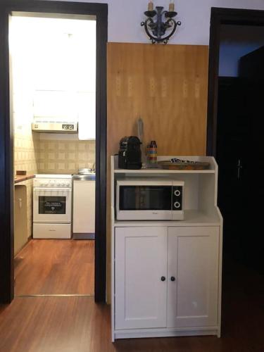 uma cozinha com um armário branco com um micro-ondas em Val D’Avio Home em Temù