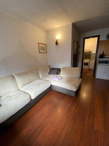 uma sala de estar com um sofá branco e pisos em madeira em Val D’Avio Home em Temù