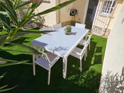 una mesa blanca y sillas en un césped con plantas en Casa Sebastian, en L'Escala