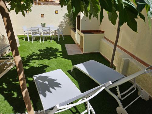 un patio con mesa y sillas en el césped en Casa Sebastian, en L'Escala
