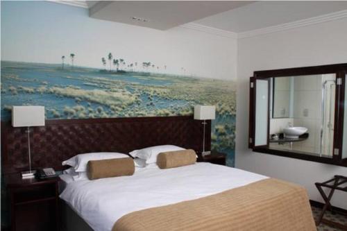 a bedroom with a large bed with a painting on the wall at Phakalane Golf Estate Hotel Resort in Gaborone