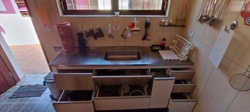 a kitchen with a sink and a counter top at Casa Rosa de Peruíbe - Casa de Temporada 3 dormitórios, 10 hóspedes, piscina, wi-fi, netflix, 800 metros da praia in Peruíbe