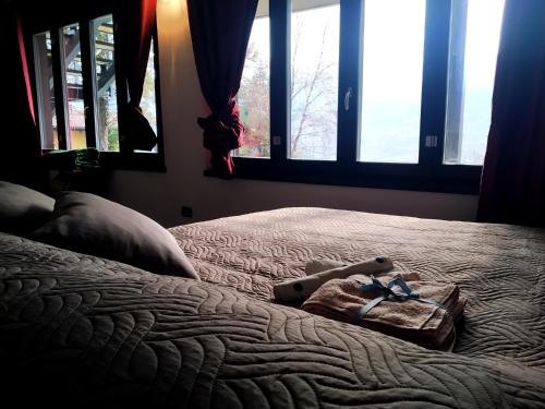 1 dormitorio con 1 cama con toalla y ventanas en Serok: Casa nel Bosco con Bio Sauna en Civo