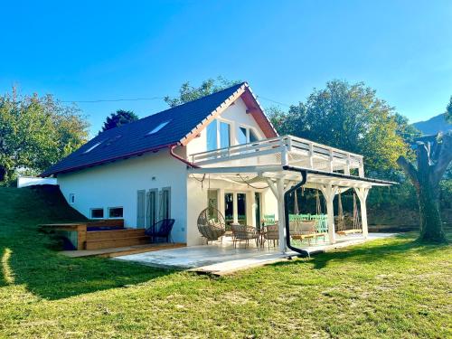 a small white house with a porch and a deck at Bohemian Eco lodge át lake Balaton in Kisapáti