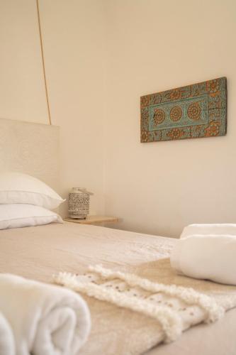 a bed with white sheets and a picture on the wall at B&B Casa do Cerro in Moncarapacho