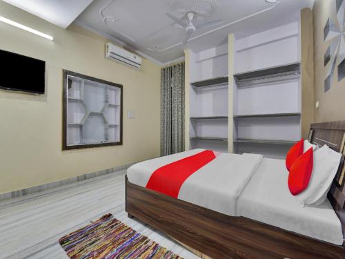 OYO Flagship Hotel Hastinapur Residency في جايبور: غرفة نوم بسرير وتلفزيون بشاشة مسطحة