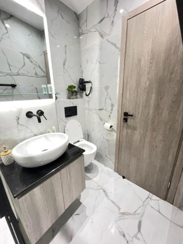 a bathroom with a sink and a toilet and a mirror at Zeos finest jacuzzi Suite in Athens