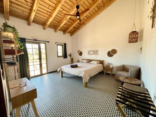 a bedroom with a bed and a chair in a room at Mama Adama - Alpaca Farm & Hotel in Grândola