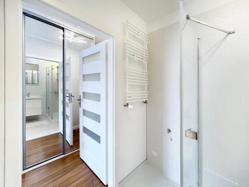 Łazienka z białymi ścianami i szklanymi drzwiami w obiekcie Apartament Neon w Szczecinie