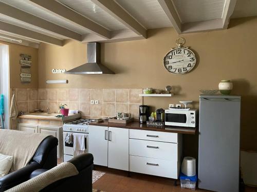 une cuisine avec des placards blancs et une horloge murale dans l'établissement La belle Charentaise, à Vaux-Rouillac