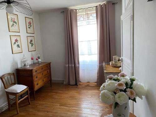 a living room with a vase of flowers and a window at La belle Charentaise 