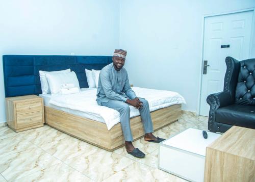 een man op een bed in een kamer bij CIS Apartments in Abuja