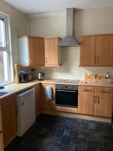La cuisine est équipée de placards en bois et d'un four avec plaques de cuisson. dans l'établissement En-suite room near, à Cardiff