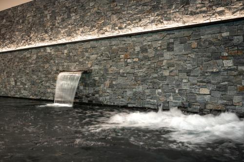 a stone wall with a waterfall in the water at Melchtal Resort Apart Hotel in Melchtal