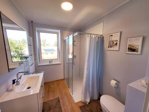 baño blanco con ducha y lavamanos en Unsere neue Ferienwohnung Hereinspaziert 