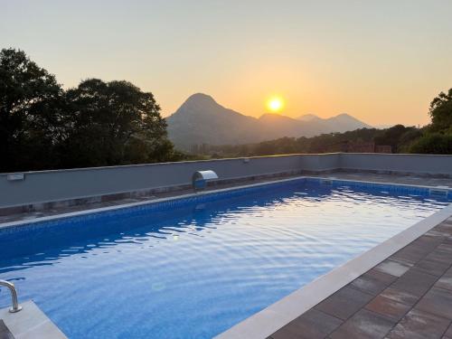 a swimming pool with the sunset in the background at Villa Ellie in Ljubuški