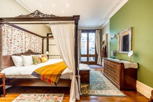 a bedroom with a canopy bed and green walls at The Regency Studio at 82 Cathedral in Cardiff