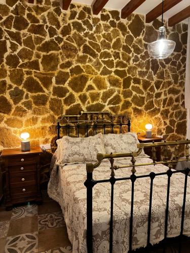 a bedroom with a bed and a stone wall at La Casilla del San Antón in Níjar