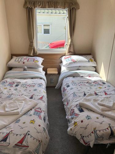 two beds in a small room with a window at Parkdean cherry tree holiday park Burgh castle Great Yarmouth in Belton