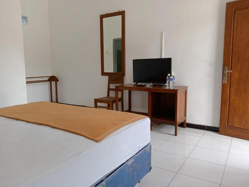 1 dormitorio con 1 cama y escritorio con TV en Hotel Tentrem Syariah en Probolinggo