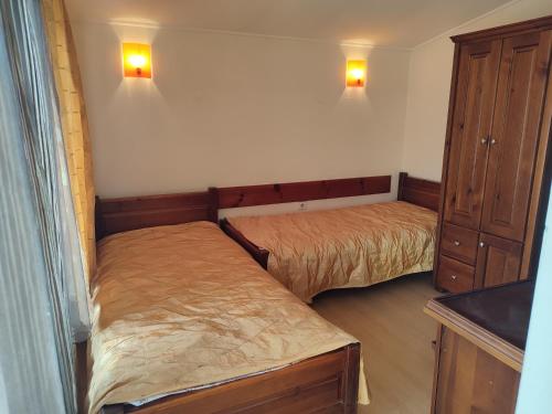 a bedroom with two beds and a cabinet and lights at Къща за гости M-Stone in Bansko