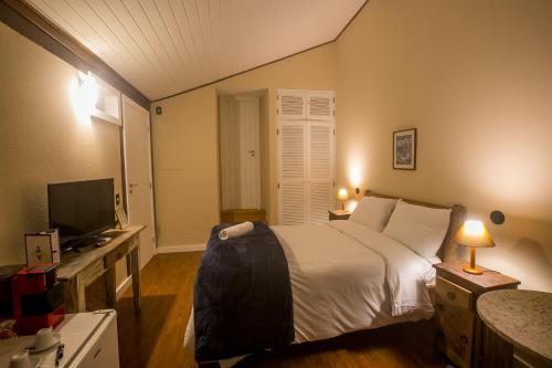 a bedroom with a bed and a desk with a television at Villa Don in Petrópolis