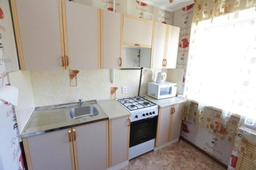 a small kitchen with a stove and a microwave at Строймарт in Petropavlovsk
