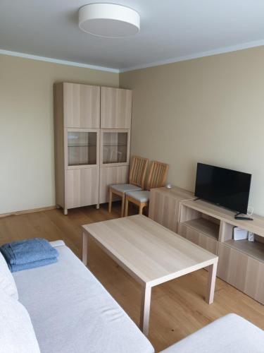a living room with a couch and a table and a tv at Ozolu apartement in Kandava