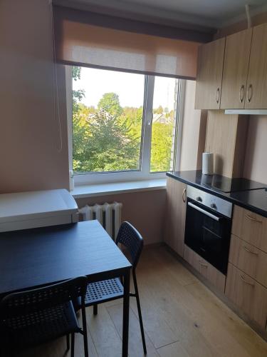 una pequeña cocina con mesa y ventana en Ozolu apartement, en Kandava