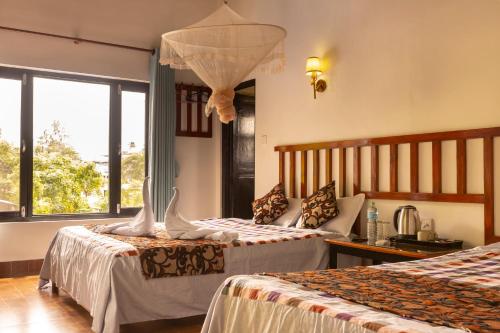 una camera d'albergo con due letti e una finestra di Hotel Parkside & Swimming Pool-Between Greenery and Azure ,Your Perfect Retreat a Chitwan