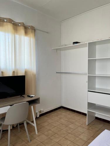 a white room with a desk and a television and a room with shelves at NM-Housing in Saint-Denis