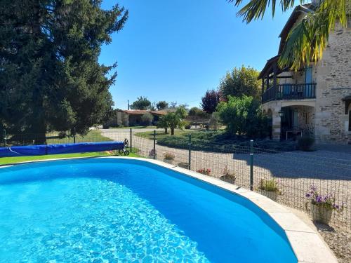 une grande piscine bleue devant une maison dans l'établissement La Salabertie, à Bagnac