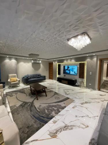 - un salon avec une télévision, un canapé et une table dans l'établissement Bright apartment ( شقة واسعة من 3 غرف ), au Caire