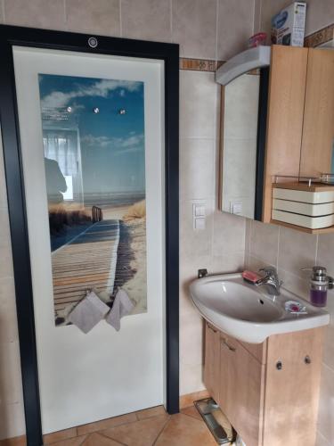baño con lavabo y una foto de la playa en Ferienwohnung *Zur Weinbergstraße*, en Lauta