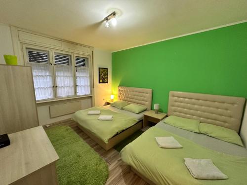 two beds in a room with green walls at Casa Bella in Palić