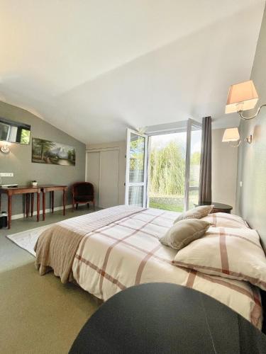 une chambre avec un grand lit et une grande fenêtre dans l'établissement Chambres Domaine de Laléard, à Saint-Hilaire-de-Villefranche