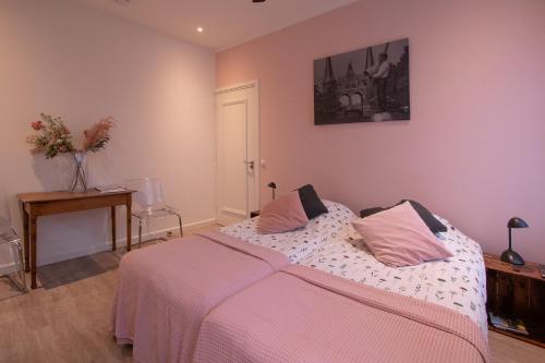 a bedroom with a bed with pink sheets and a table at Lekkerwegbijleeuwen, 1 minuut naar hartje centrum in Sneek