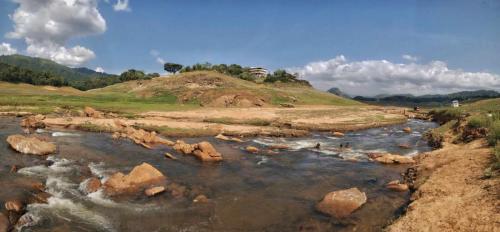 a river with rocks in the middle of a field at Victoria Views Resort Kandy in Digana