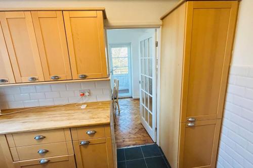 a kitchen with yellow cabinets and a hallway at Traditional 3 Bed Flat In Highgate in London