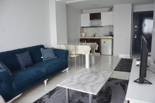 uma sala de estar com um sofá azul e uma cozinha em Hera Rezidans em Kırac
