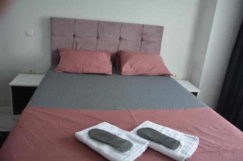 un letto con lenzuola rosa e grigio e cuscini rosa di Hera Rezidans a Kırac