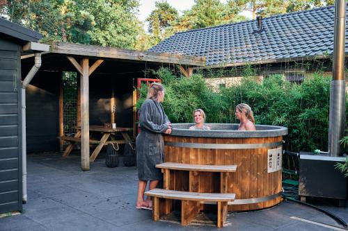 two women standing in front of a hot tub at ZEN-bungalow no 6 met sauna en hottub in Rheezerveen