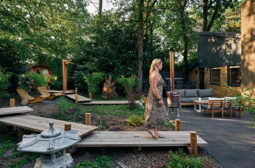 a woman standing on a wooden table in a garden at ZEN-bungalow no 6 met sauna en hottub in Rheezerveen