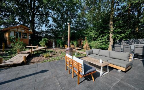a patio with a couch and benches in a yard at ZEN-bungalow no 6 met sauna en hottub in Rheezerveen