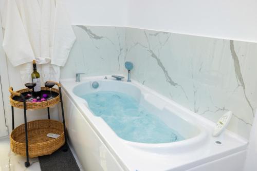 El baño incluye bañera con agua azul. en Apollo 2 bd jacuzzi suite en Athens