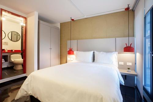 a bedroom with a large white bed and a toilet at Villaviciosa Hotel Boutique in Pasto