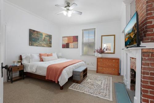 a white bedroom with a bed and a fireplace at Redstick Cottage in Baton Rouge